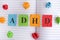 Abbreviation ADHD on notebook sheet with some colorful crumpled paper balls around it