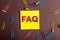 The abbreviation FAQ is written on a dark fonen rocky sticker near multi-colored paper clips. Business concept