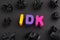 The abbreviation IDK I don`t know made out of polymer clay letters with some black crumpled paper balls around it