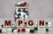 Abbreviation MPGN text on wooden cubes on a light background with a jar of pills