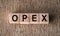 Abbreviation OPEX Operational Expenditures - text on wooden cubes on a brown background. Business concept