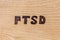 An abbreviation PTSD - post traumatic stress disorder - burned by hand on flat wooden board