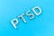 Abbreviation PTSD - post traumatic stress disorder - laid with silver metal letters on blue flat surface