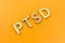 Abbreviation PTSD - post traumatic stress disorder - laid with silver metal letters on yellow flat surface
