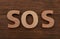 Abbreviation SOS made of letters on wooden table, top view