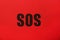 Abbreviation SOS Save Our Souls written on red background, top view