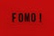 Abbreviation word FOMO on transparent plastic on red background. It means Fear Of Missing Out, non-stop internet surfing. Concept