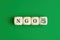 The abbreviation word NGO nongovernmental organization written on wooden cubes with people icon on green background