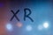 An abbreviation xr for extended reality handwritten on blue night wet window glass