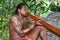 Aborigine actor performs music with traditional didgeridoo musical instrument in the Tjapukai Culture Park in Kuranda, Queensland,