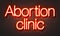 Abortion clinic neon sign on brick wall background.