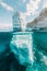 Above and below: split view of white iceberg floating in clear blue sea