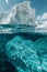 Above and below: split view of white iceberg floating in clear blue sea