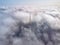 Above the clouds on a sunny day, view from a drone. High communications tower antenna rises above the clouds