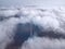 Above the clouds on a sunny day, view from a drone. High communications tower antenna rises above the clouds