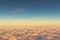 Above clouds, view from pilot cabine in airplane. Aerial view above clouds during the sunrise or sunset. Blue sky, white clouds