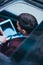 Above head perspective of a businessman working on his tablet while sitting in his black limo