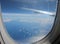 Above the ocean and the clouds. Airplane window with little snowflakes