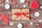 Above overhead close up view photo of wrapped in kraft paper box with red bow and romantic accessories around on wooden brown desk