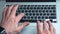 Above shot of man using laptop computer on office table background. Man typing on laptop keyboard. Top view