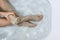 Above shot of woman`s legs and hands holding luffa sponge in bathtub