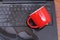 Above view of coffe drop and a red cup of coffe over the laptop, damage liquid wet and spill on keyboard, accident