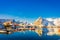 Above view of some wooden buildings in the bay with boats in the shore in Lofoten Islands surrounded with snowy