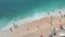 Above view of tourists on the beach enjoying turquoise sea and waves