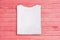 Above view of white folded blank t-shirt on pink wooden background. Female tshirt design template