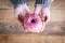 Above view of woman`s hand taking two tasty pink donuts full of candy - vertical point for junk sweet cakes - wooden defocused