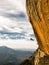 Abseiling a negative yellow rock wall with mountains on backgrou after rock climbing