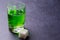 Absinthe green liquor in glasses. Alcoholic hallucinogenic beverage. Dark background. Pieces of white sugar. Copy space