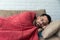 Absolute solitude. Side view of a depressed unhappy sad man lying on the sofa and hugging a blanket while feeling lonely, sad and