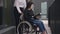 Absorbed concentrated disabled woman reading paperwork as unrecognizable assistant walking pushing wheelchair