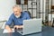 Absorbed pensive senior businessman in smart casual shirt sits at the desk