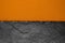 Abstract background composition of divided in the half matt dark orange color paper and black stone with copy space