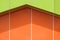 Abstract background pattern of vibrant green and orange aluminum composite tiles wall outside of modern building