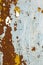 Abstract background texture of vertical grungy rusting metal plate with peeling paint and extensive corrosion with rust streaks.