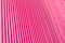 Abstract background of vertical relief metal ribs covered with glamorous pink color.
