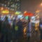 Abstract blurred silhouette of girl under red umbrella, modern city at rayny night, defocused urban bokeh lights