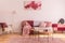 Abstract burgundy and pastel pink painting on empty white wall of fashionable living room interior with classy armchair and