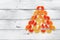 Abstract Christmas tree made of jelly candies on a white old wooden background. Top view, flat lay. Marmalade citrus slices