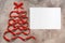 Abstract Christmas tree made from red silk ribbon and blank card mockup. Beige rustic background. Creative new year template. Top