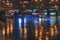 Abstract dark background of modern city at rayny night, bright illumination, reflection on wet asphalt, blurred