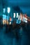 Abstract dark blurred background of city street in evening, pedestrian street, unidentified people, street lamps shop