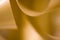 Abstract, defocused, yellow gold curling party ribbon with blurred, textured, bokeh background