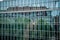 Abstract distorted reflection of historic house and green trees in mirrored glass wall of modern corporate building