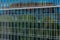 Abstract distorted reflection of historic house and green trees in mirrored glass wall of modern corporate building