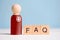 Abstract doctor with a medicine and an inscription: answers to popular questions - FAQ. A wooden figurine with cubes on a blue