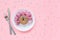 Abstract funny face of woman from donut with eyes and hair from centimeter tape on plate, cutlery on pink background. Diet or